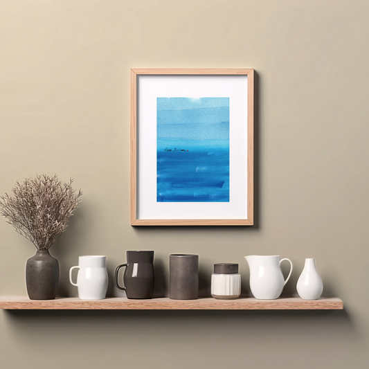 Framed abstract painting in blue with expressive brushstrokes and handwritten word Here I Am with a dot of red paint, spiritual modern art print, hanging on wall above a wooden counter top.