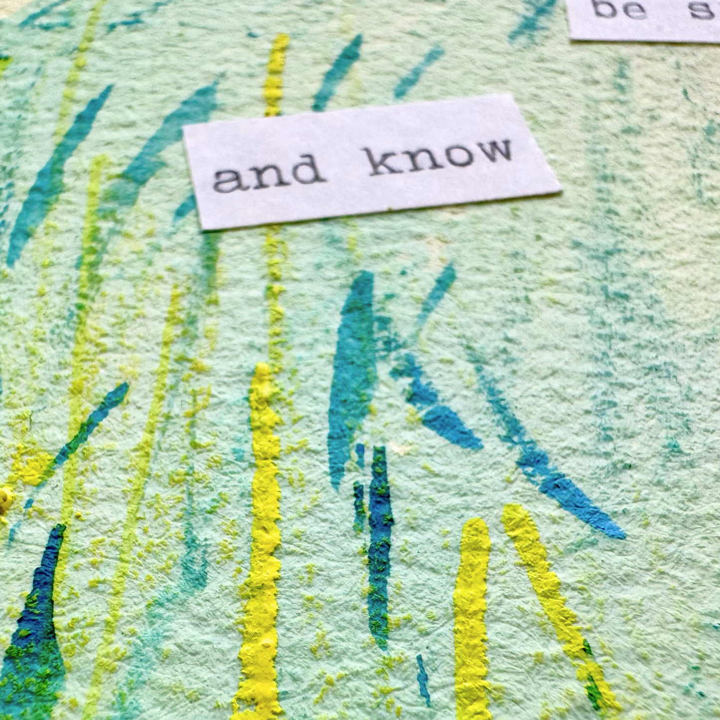 Close up of abstract painting with typewritten text 'be still and know that I am God' on a textured watercolour paper