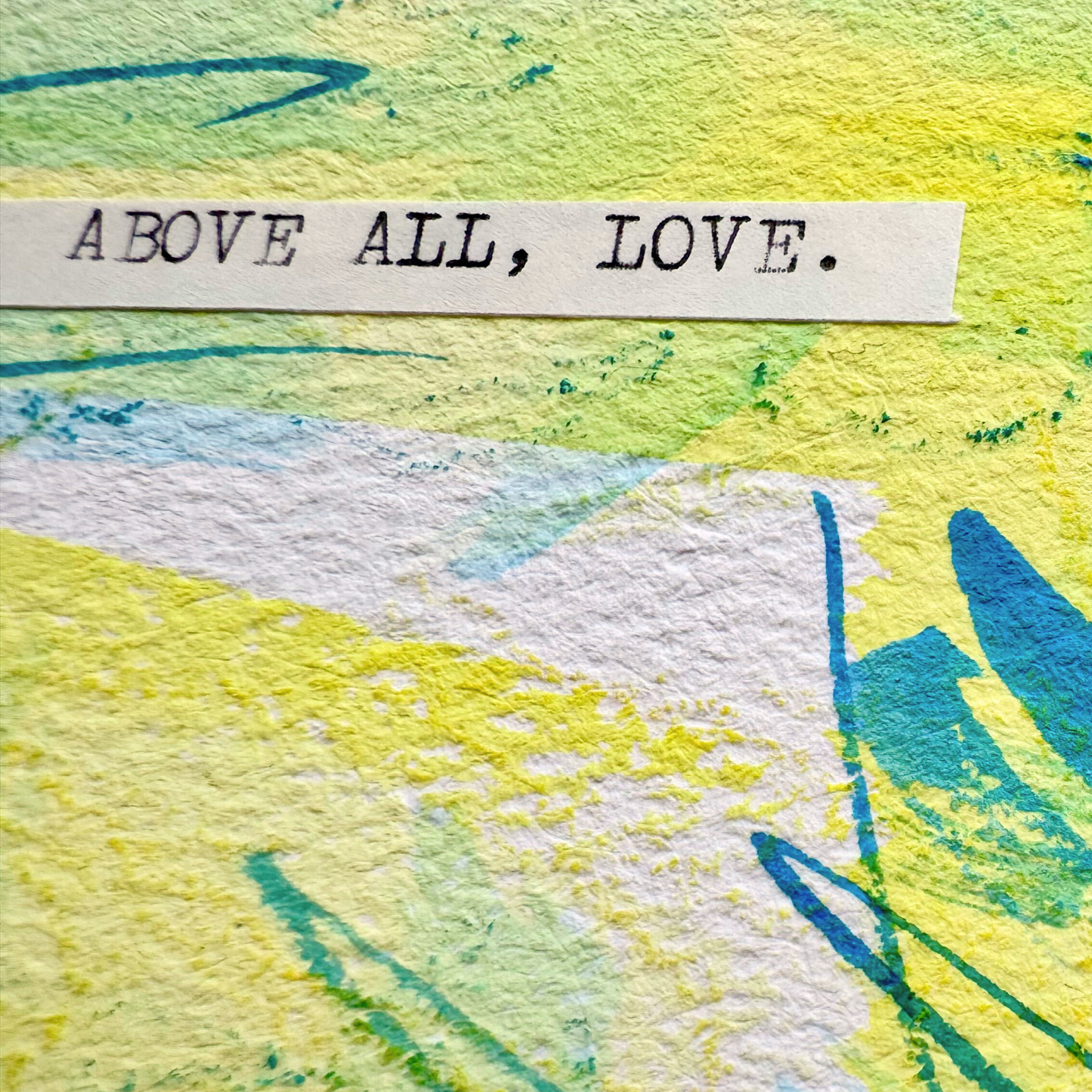 Abstract mixed media painting with typewritten text 'Above All, Love' on a textured cold pressed watercolour paper