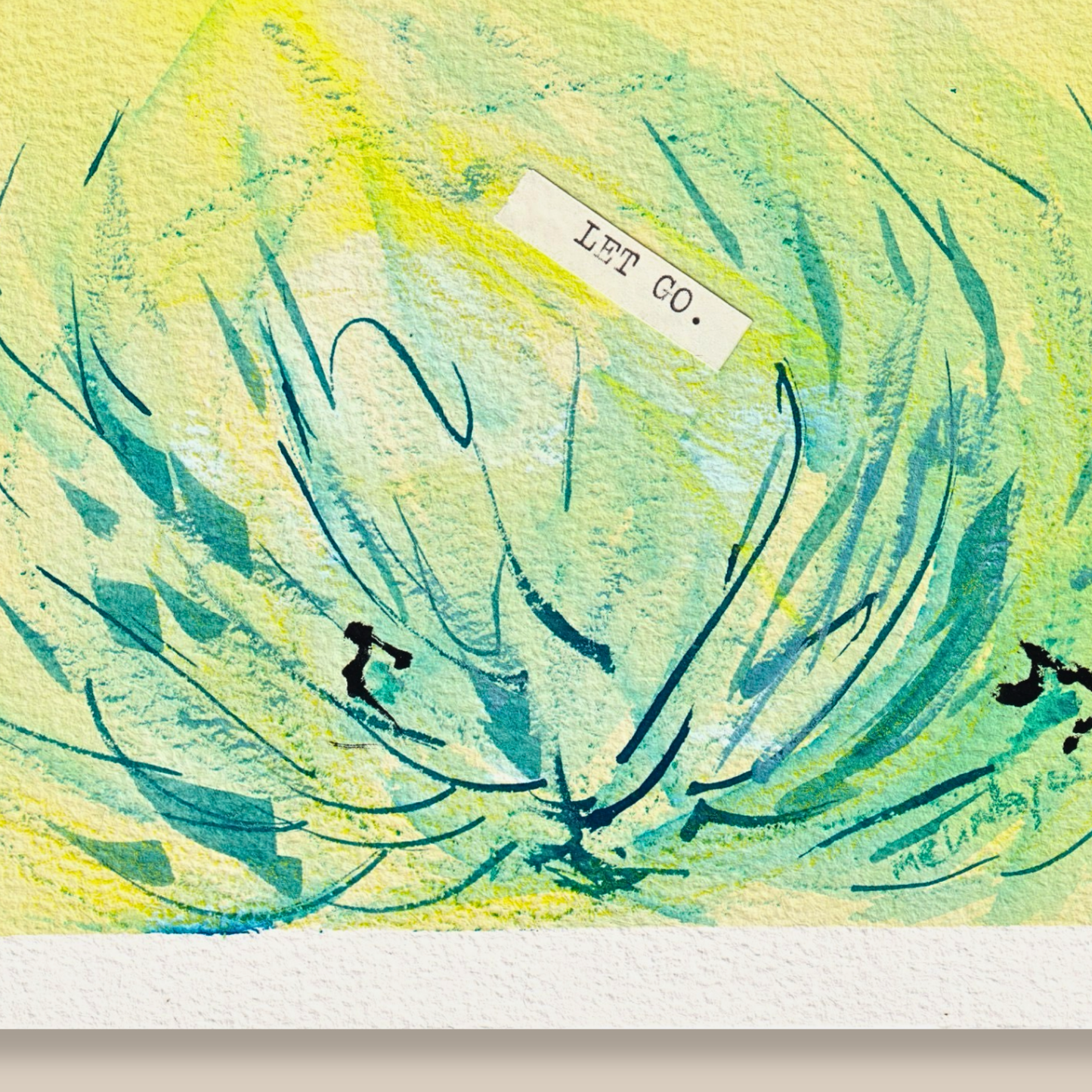 Close up of abstract mixed media painting with typewritten text 'Let Go' on a textured cold-pressed watercolour paper on a beige background
