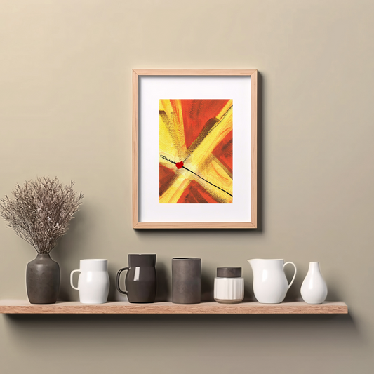 Framed reddish orange and golden yellow abstract painting art print with expressive brushstrokes with a dot of red paint, spiritual modern art print, hanging on wall above a wooden counter top.
