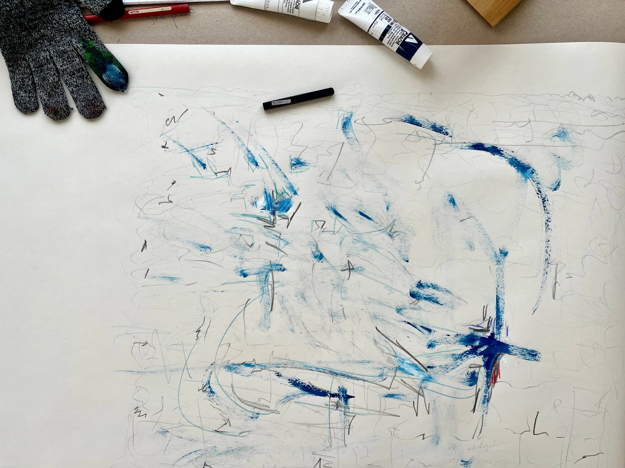 Intuitive abstract painting on paper with blue and black brush strokes, surrounded by art supplies by Melinda Yeoh Art from monologue\worship/conversations series