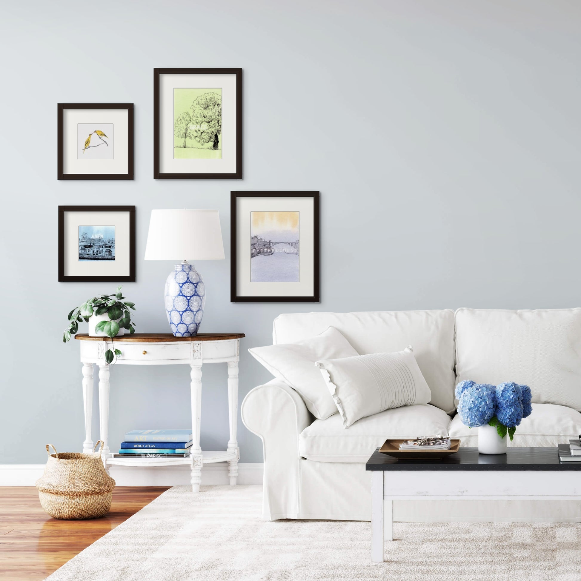 Image: bright, rustic, white colour living room with soft blue colour flowers. A series of line drawing framed artwork above the sofa.