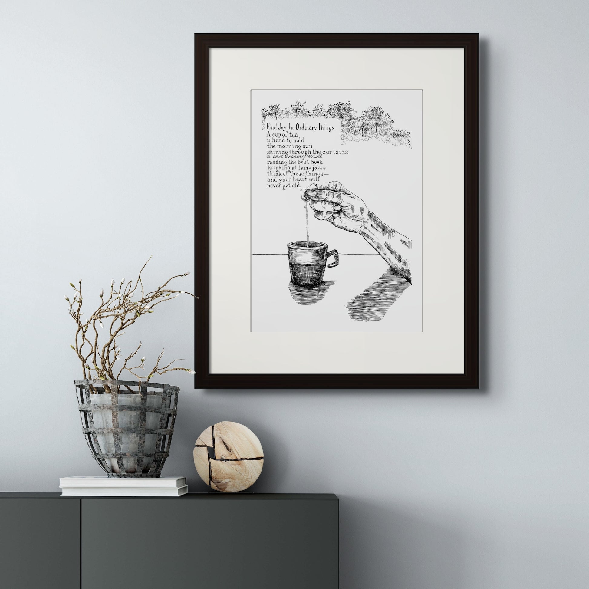 Image: giclée art print with black frame and cream colour mat of a hand and teacup with poem