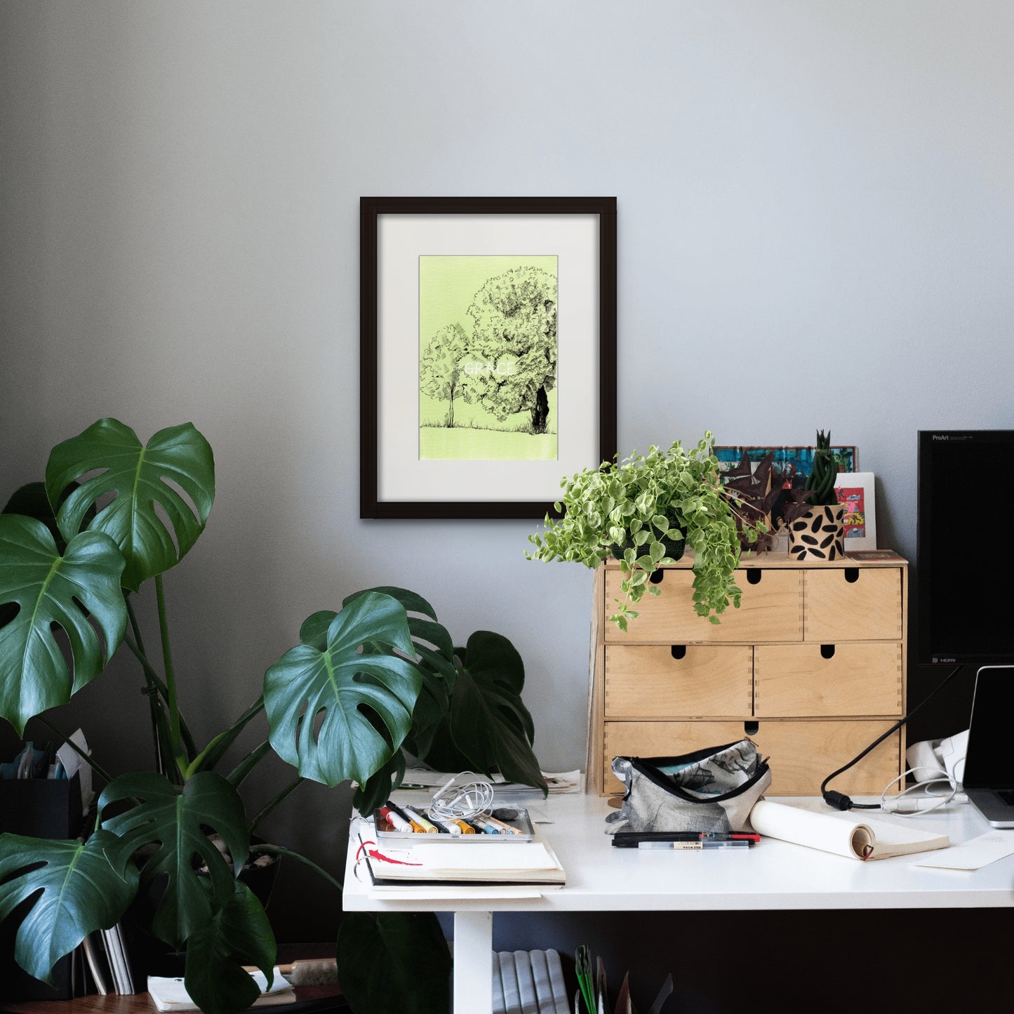 Image: Line drawing with watercolour giclée art print with black frame and cream colour mat of a peaceful, green nook at Parque da Cidade do Porto (Porto City Park). Art print in a home office work desk setting.